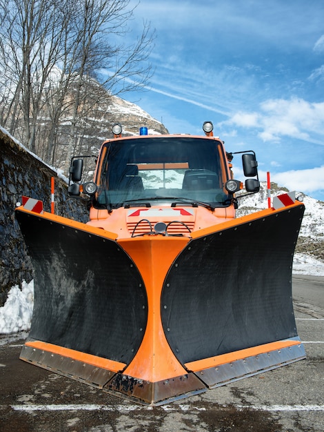 Caminhão pequeno laranja usando arado de neve