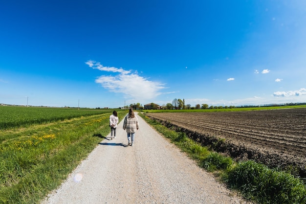 Caminhe no campo em um dia ensolarado entre dois amigos irreconhecíveis