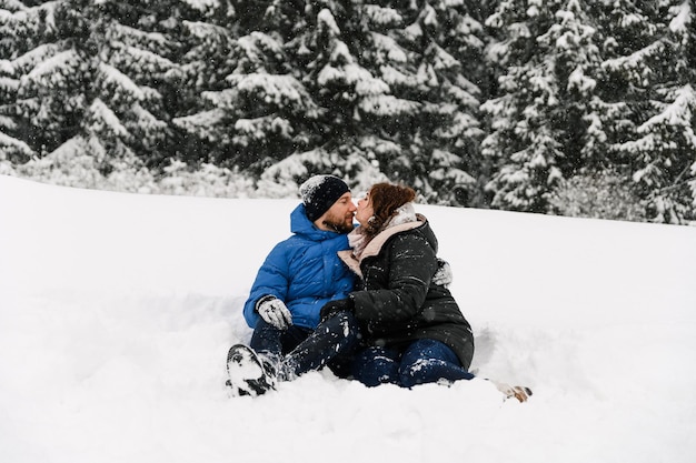 Caminhe no inverno. Abraçando o casal, apreciando a queda de neve. Homem e mulher se divertindo na floresta gelada. Encontro romântico no inverno. Humor de Natal de uma jovem família. Conceito de amor e lazer
