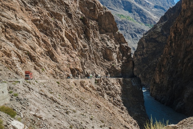 Caminhões paquistaneses que viajam na estrada pavimentada ao longo da montanha perto do penhasco na estrada de Karakoram.