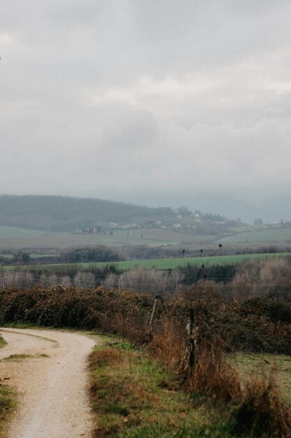 un camino de campo con una vista del campo y una granja en el fondo