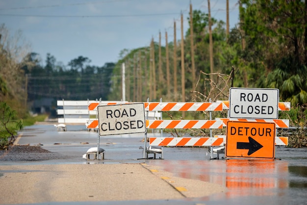 Camino cerrado por obras viales y peligro de inundación con señales de advertencia que bloquean la conducción de automóviles