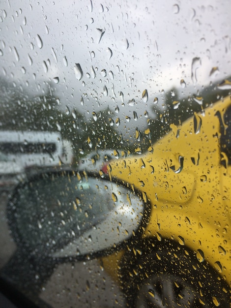 El camino con los coches se fotografía a través del parabrisas salpicado por la lluvia del coche.