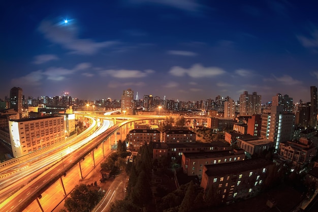 Camino elevado por la noche con senderos de luz de autos en la ciudad moderna