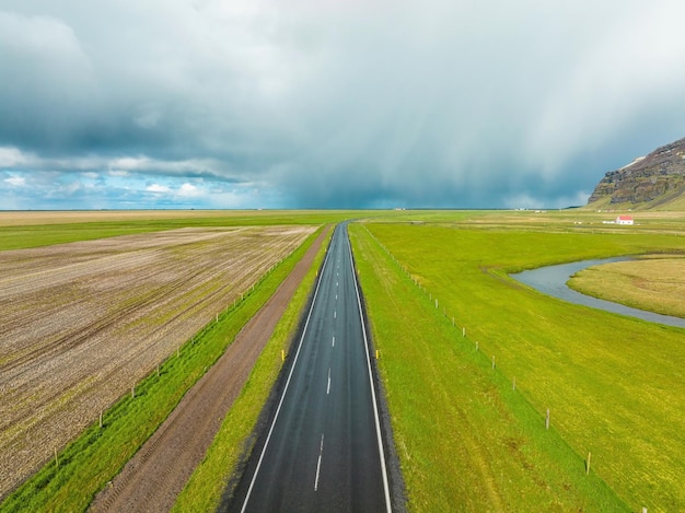 Camino sin fin hacia las montañas nubladas y las colinas de islandia durante el clima soleado y nublado