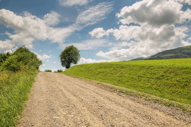 Foto camino con grava se extiende hasta la colina verde