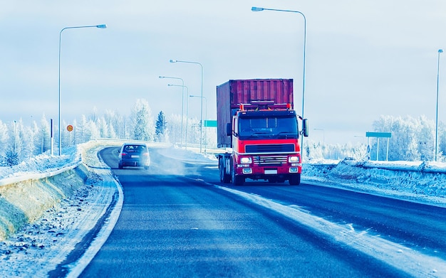 Camino de invierno con nieve. Camión en Finlandia. Camión y paisaje frío de Laponia. Bosque de Europa. Paseo por la autopista de la ciudad finlandesa. Carretera y ruta callejera nevada. Entrega en conducción cuesta abajo