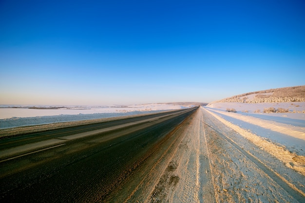 Camino de invierno a través de campos nevados y bosques.