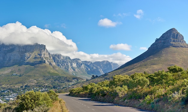 Un camino a lo largo de una montaña y naturaleza verde con un cielo azul nublado y espacio para copiar Hermoso paisaje de una tranquila carretera asfaltada cerca de las plantas y el desierto en un día de verano