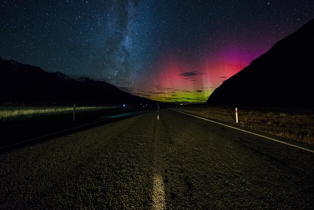 Foto camino en medio de montañas iluminadas contra el cielo nocturno