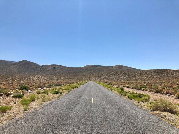 Foto camino en medio del paisaje contra un cielo azul claro