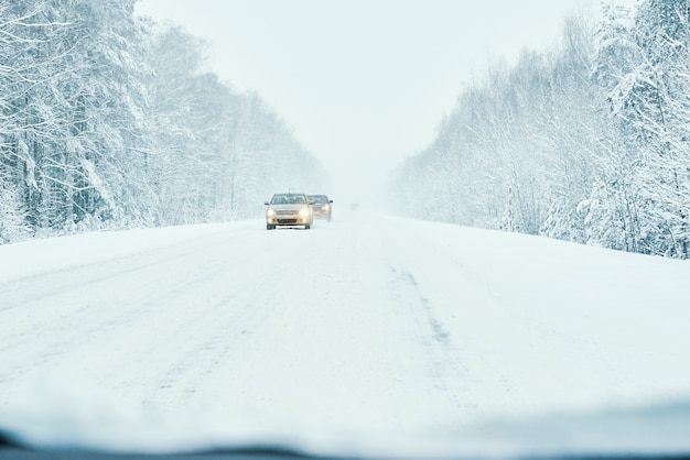 Camino nevado en bosque de invierno con coche en movimiento