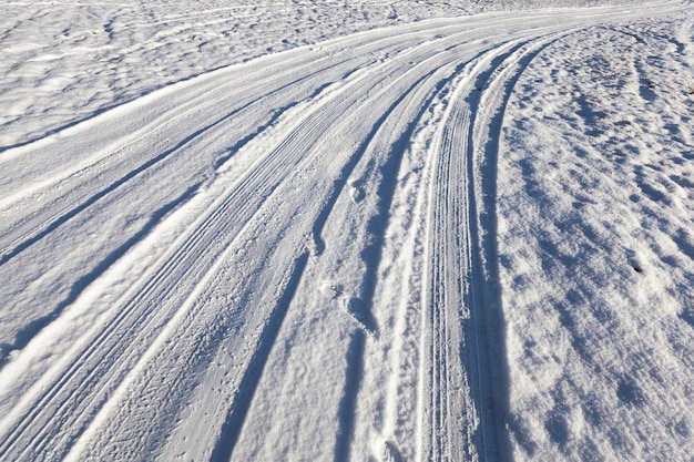 Camino nevado en el campo, dirigido a la izquierda. En época de invierno del año, las huellas de los neumáticos de los automóviles son visibles en la nieve.