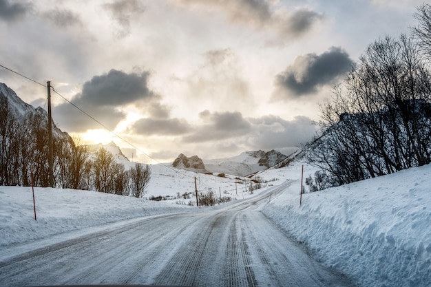 Camino de nieve sucia con luz solar en las montañas