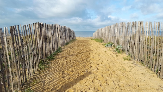 Camino peatonal de arena para acceso a la playa protegido por laterales de madera