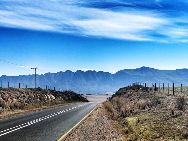 Foto el camino que conduce hacia las montañas contra el cielo azul