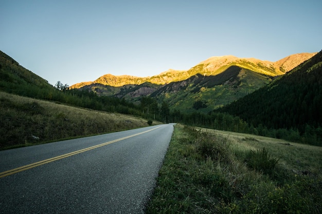 Foto camino que conduce hacia las montañas contra un cielo despejado