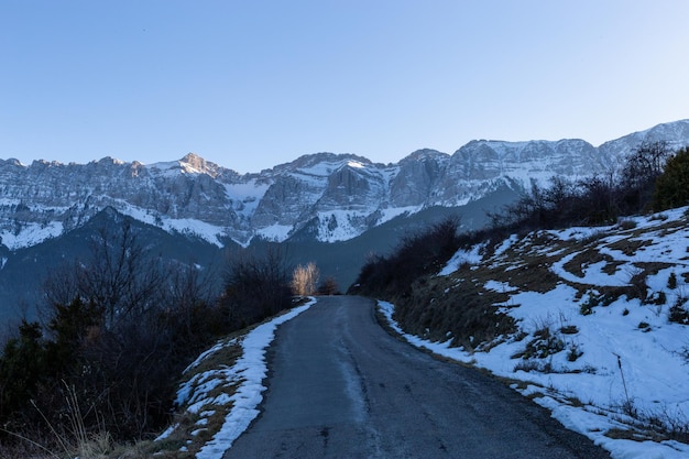 Camino que cruza la cima de unas montañas nevadas durante la puesta de sol