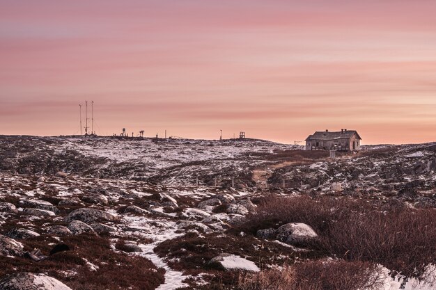 Camino resbaladizo a una estación meteorológica abandonada en una colina. El duro paisaje de la tarde polar. Rusia.