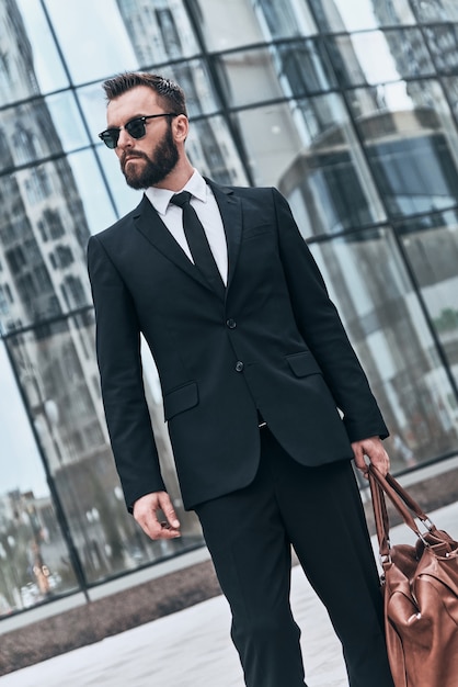 camino a la reunión de negocios. apuesto joven en traje completo y gafas de sol