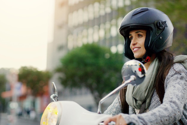 El camino siempre te hará ver lo que es realmente importante Foto de una mujer joven y atractiva que conduce su scooter por la ciudad