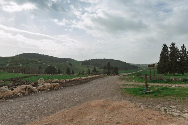 Camino de tierra y campo verde en el fondo de las nubes en Israel