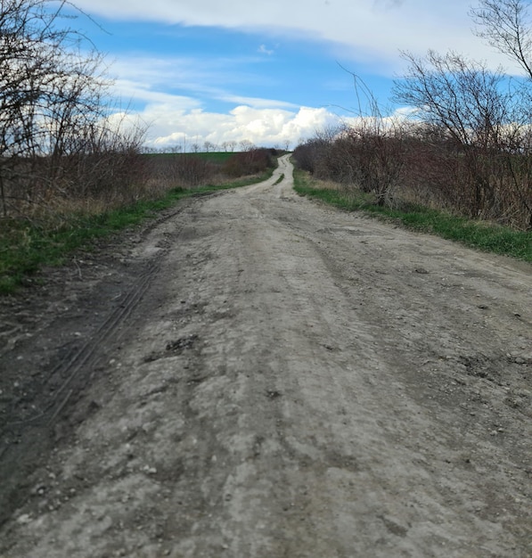 Foto un camino de tierra con un cielo azul y algunas nubes.