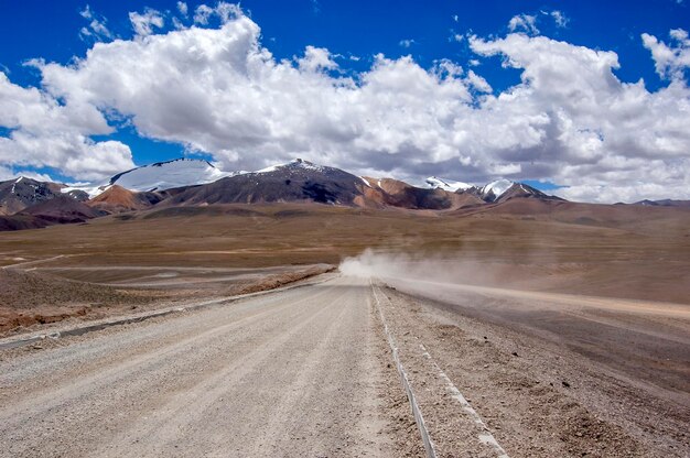 Foto un camino de tierra conduce a la hermosa y espectacular montaña de nieve en la distancia