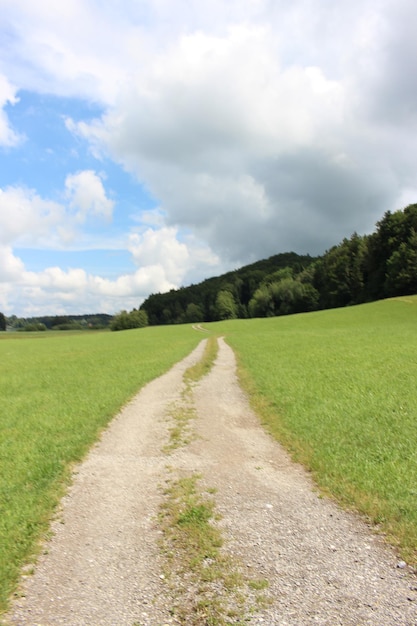 Foto camino de tierra en medio de un campo contra el cielo