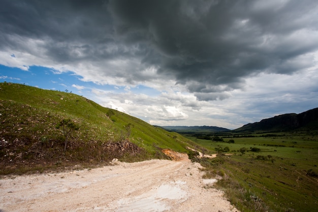 Camino de tierra rural con cielo oscuro de tormenta