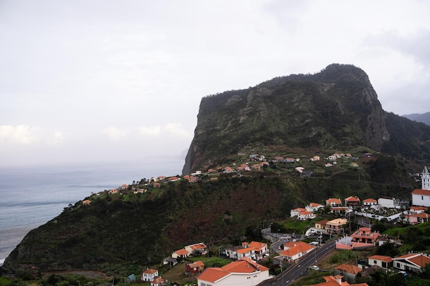 Camino a través de una colina con casas frente al mar en un día nublado en Madeira, Portugal