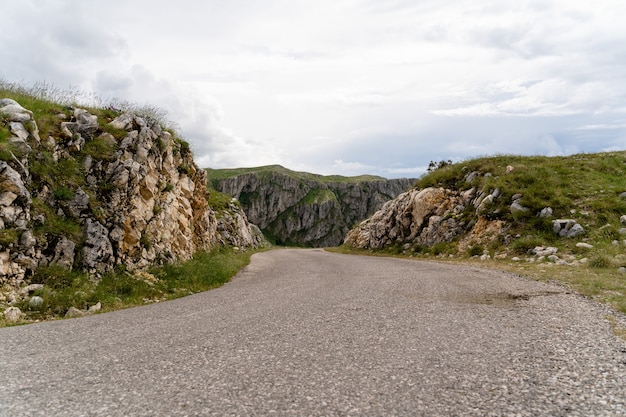 Camino a través de formaciones geológicas y montañas rocosas bajo el cielo nublado