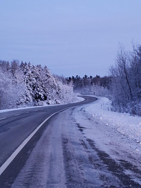 Foto camino vacío a lo largo de un paisaje cubierto de nieve