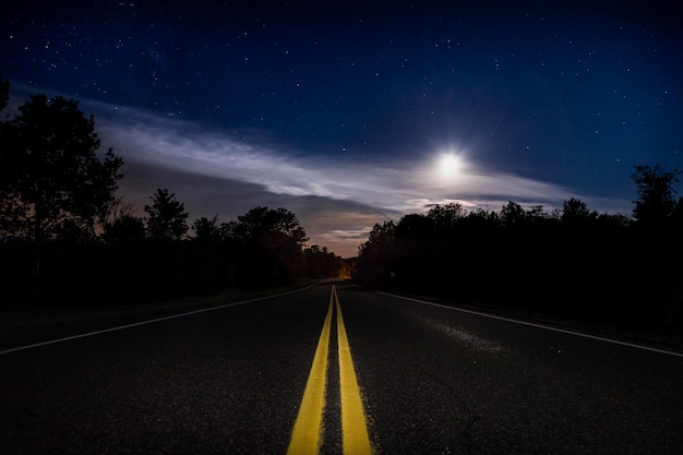 Foto camino vacío en medio de plantas contra el cielo nocturno