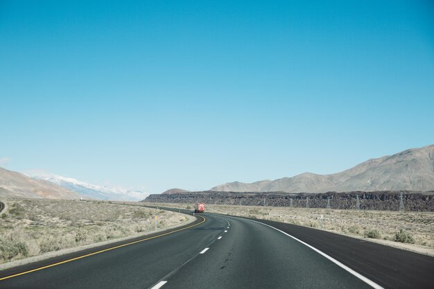 Foto camino vacío por las montañas contra el cielo azul claro