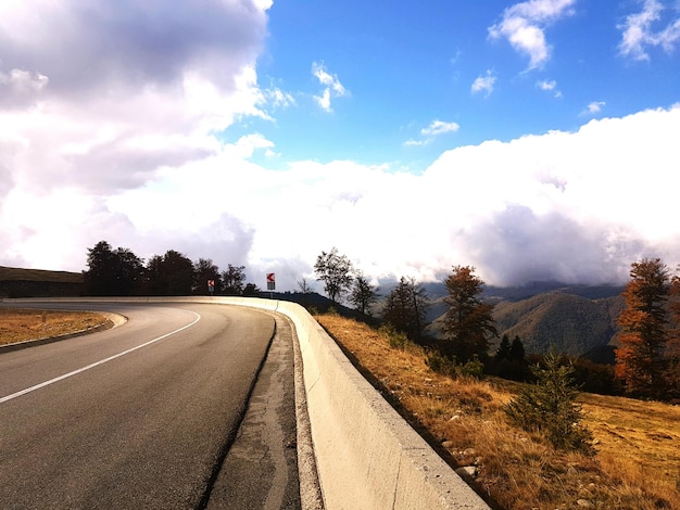 Foto camino vacío y montañas contra el cielo nublado