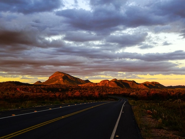 Foto camino vacío por las montañas contra el cielo durante la puesta de sol