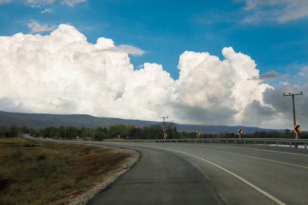 Un camino vacío que conduce a grandes montañas con grandes nubes y cielo.