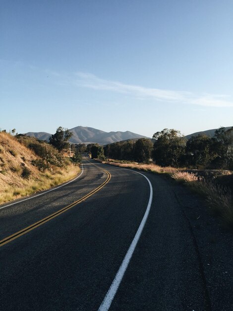 Foto camino vacío que conduce hacia las montañas.