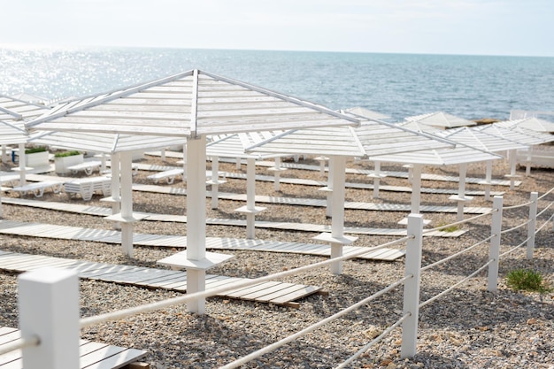 Caminos de sombrillas de playa de madera blanca y tumbonas en el océano a orillas del mar