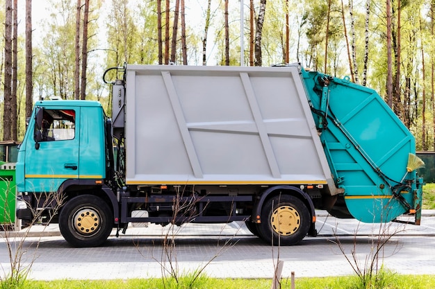 Un camión de basura recoge basura en una zona residencial Carga de mussar en contenedores en el coche Recogida y eliminación separada de basura Vehículo de recogida de basura