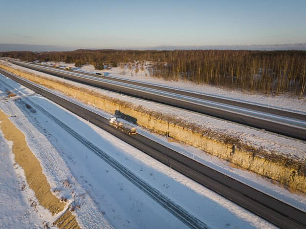 Un camión de combustible conduce a lo largo de la autopista fuera de la ciudad en una foto de invierno de un dron