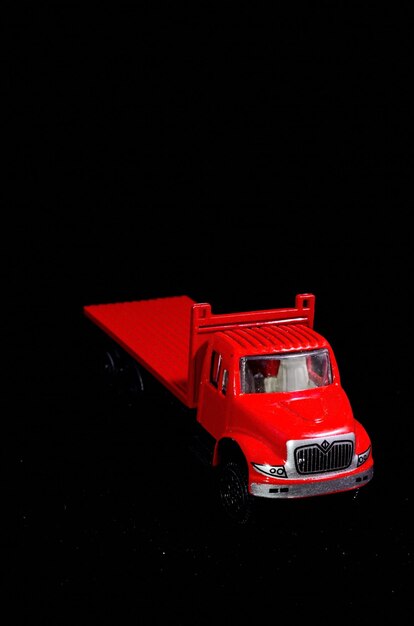 Camión de figurillas de juguete rojo sobre un fondo negro