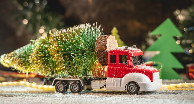 Un camión de juguete rojo y blanco transporta un árbol de Navidad