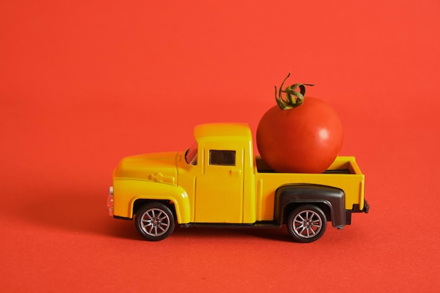 Camión retro y pequeños tomates cherry sobre fondo rojo cosechando publicidad de ketchup