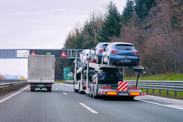 Camión transportador de vehículos en carretera. Transportista de vehículos automáticos en la calzada. Logística de transporte europea en el transporte de trabajo de acarreo. Remolque de transporte pesado con conductor en carretera.