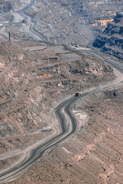 El camión volquete de la cantera de mineral de hierro se mueve en la carretera de terreno escalonado en terrazas, industria minera, minería y equipos de extracción.