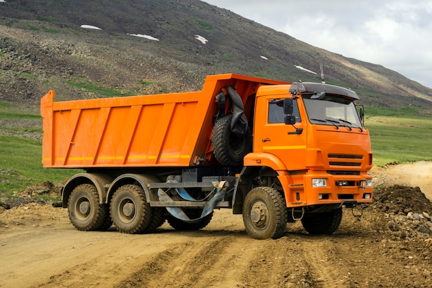 Camión volquete gira en la carretera de montaña en construcción