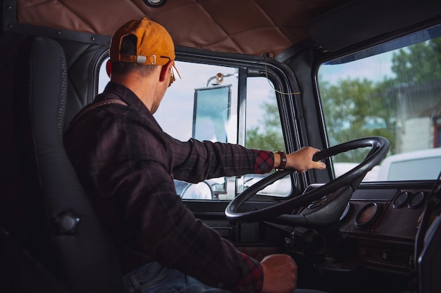 Foto camionero de 40 años dentro de la cabina del tractor semirremolque envejecido vintage