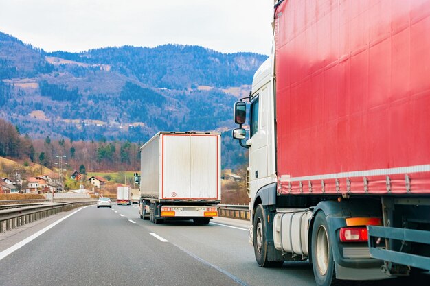 Camiones en carretera. Camionero en carretera. Camión haciendo trabajo de logística. Semirremolque con conductor. Coche de carga grande. Entrega de carga. Industria del transporte de exportación. Contenedor con mercancías cargadas en segundo plano.